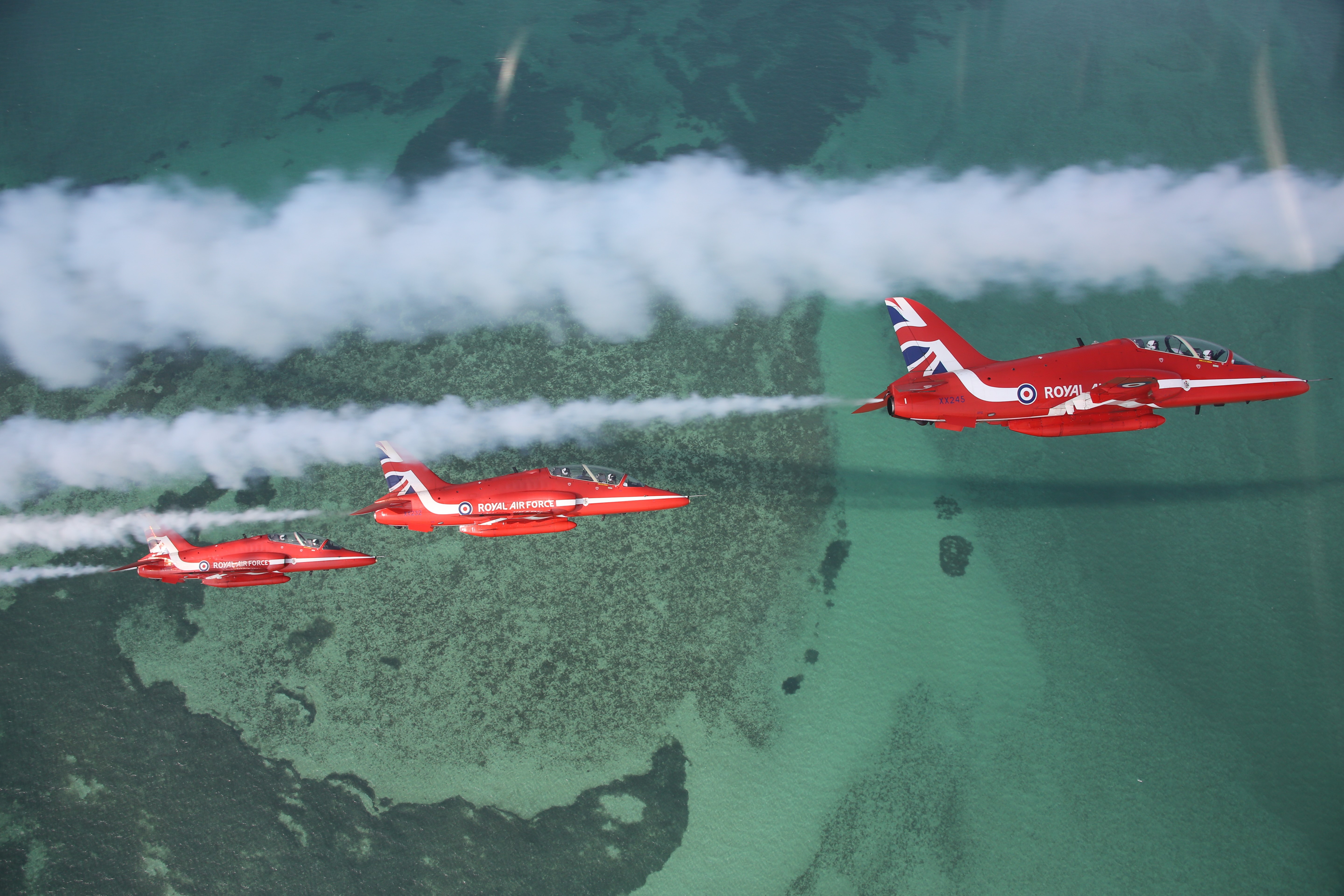 Image shows three Red Arrows performing with white smoke trails.